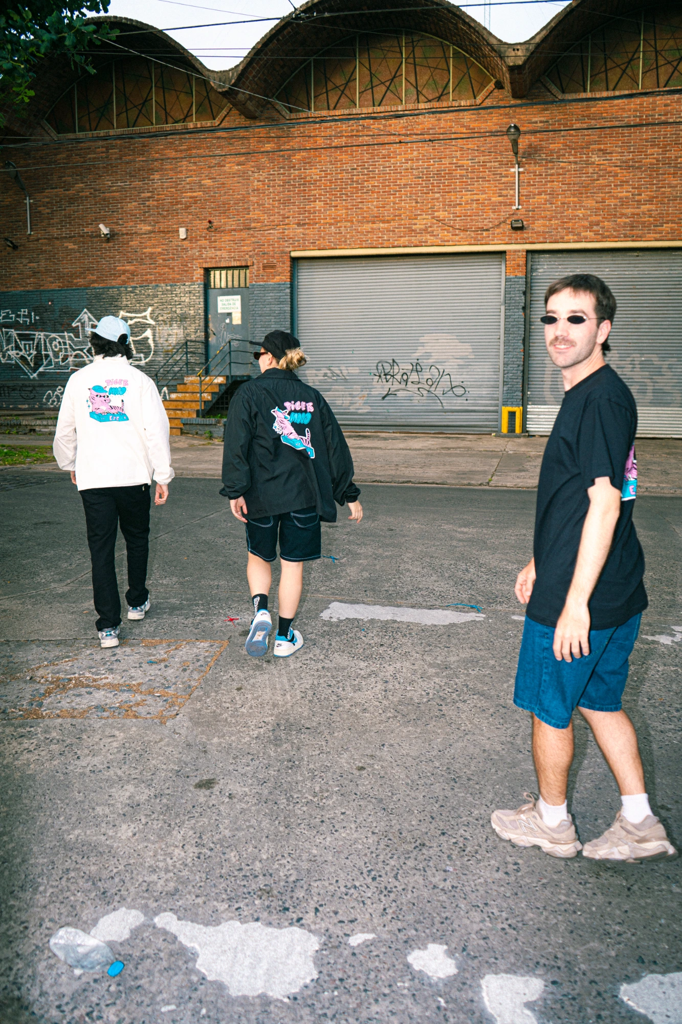 3 integrantes de Tiger Mood caminando, mostrando el dorso de la remera y camperas mood x eje